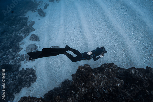 Shallow waterman doing scuba diving in deep blue sea.