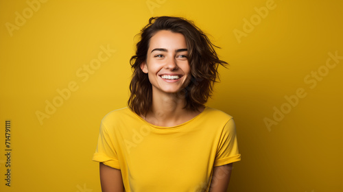 Portret studyjny młodej kobiety uśmiechniętej na żółtym tle z dużą ilością wolnego tła