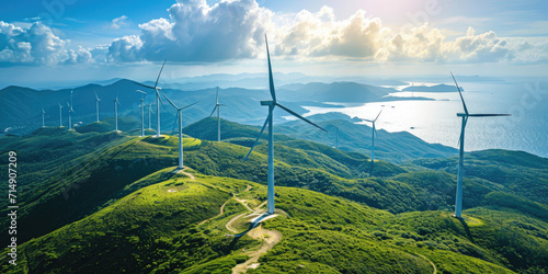 Wind turbines stand atop lush green hills with a panoramic view of the coast and sea, symbolizing sustainable energy generation.