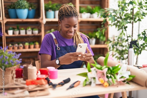 African american woman florist smiling confident using smartphone at florist
