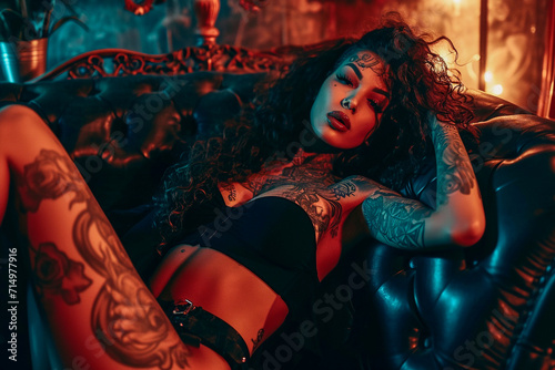 Beautiful sexy African-American model with long thick curls and tattoos lounges on a couch
