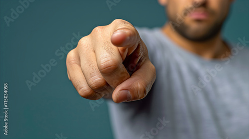 Close-up of man pointing finger directly at camera on teal background