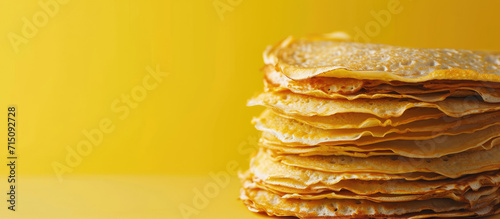 Stack of Freshly Made Golden Crepes, copy space. Golden stack of homemade crepes on a flat background.