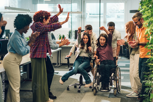Young diverse business people racing in an office chair race at work