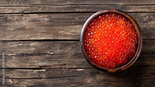 Red caviar in a plate on a wooden table, top view.