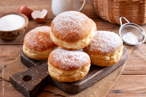 Hanukkah sweet food doughnuts sufganiyot with powdered sugar and fruit jam on a wooden board. Jewish holiday Hanukkah concept.