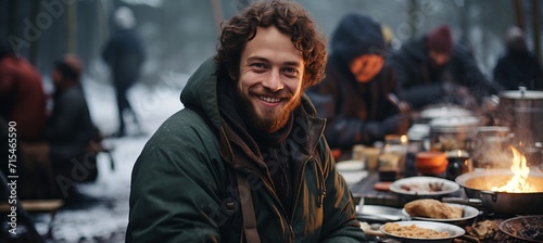Young man cooking at winter tent camp in snow forest, survival and camping concept