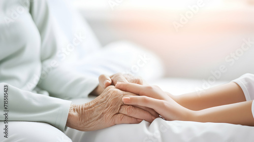 Two hands. A young woman holds the hand of an older woman. Caregiver at home. Concept of health care for senior elderly old people. Space for text white background. Generative ai.