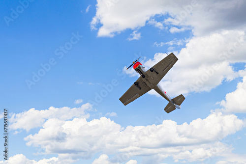 View of an aerobatic plane (aerodyne), in flight under a blue sky with white clouds. flight exhibitions 