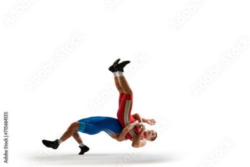 Two young man, skilled sportsman of freestyle wrestling in uniform fighting against white studio background. Concept of motion, action, combat sports, strength and power, movement,