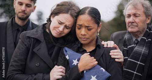 Funeral, death and support for a woman with a flag at a cemetery in mourning at a memorial service. Sad, usa and an army wife as a widow in a graveyard feeling the pain of loss or grief with a friend