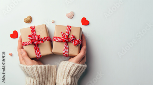 Cadeaux de Saint-Valentin tenus dans des mains féminines sur fond décoré de cœurs