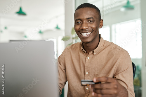 Smiling African businessman online shopping at his office desk