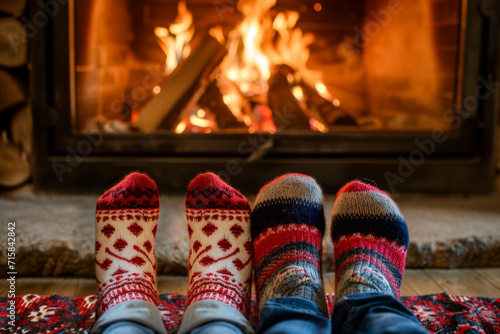vue sur des paires de pieds avec des chaussettes d'hiver dans le style de noël, feu de cheminée en arrière plan