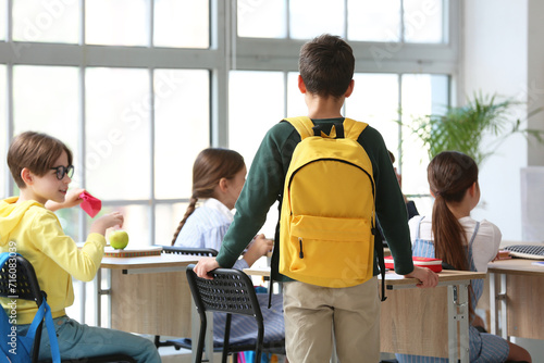 Little boy with backpack in classroom, back view