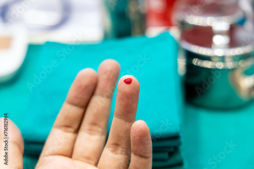 Close-up finger with blood drop at finger from lancets for sample checking blood sugar level by blood glucose meter. Diabetes testing in laboratory or clinic.