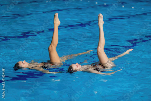 Aquatic poetry of a synchronized swimming duet, crafting a mesmerizing dance in the shimmering pool waters, a perfect blend of grace and precision