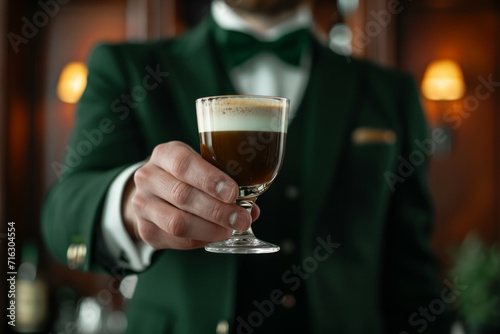 Irish coffee cocktail with an Irish bartender in green suit handing a glass of Irish coffee a cocktail made of whiskey, coffee and cream