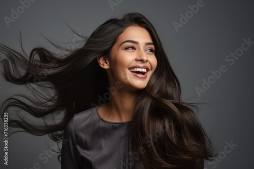 Energetic smiling young female of Indian ethnicity having long flowing hair