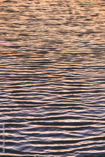 Minimalistic lake waves in the evening at sunset loya background, reflection of the sunset sky in the water