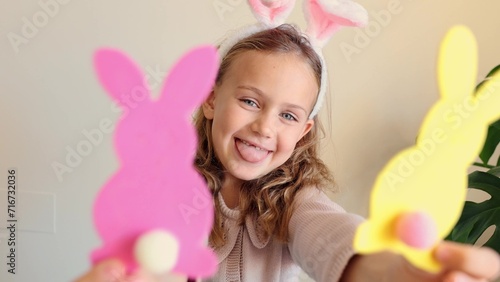 Close up hands child girl holds paper colored garland Easter bunny pompons. Excited emotional children. Rabbit years crafts for Easter party at home. Holiday Art Activity Kid. creativity hobby DIY