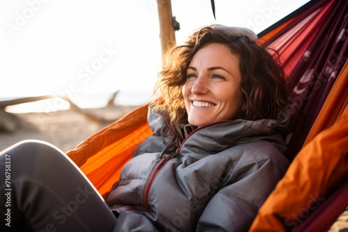 Portrait of a blissful woman in her 30s sporting a quilted insulated jacket against a relaxing hammock on the beach background. AI Generation
