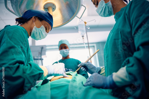 Female doctor performing surgery in operating room at medical clinic.