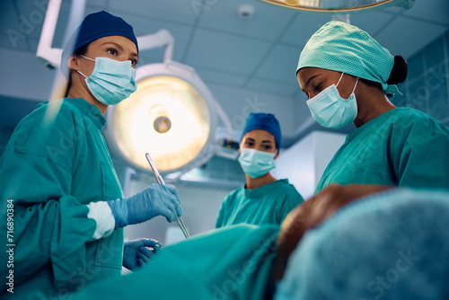 Team of female surgeons preforming surgical procedure in operating room at medical clinic.