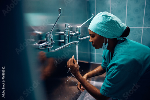 Black female doctor washing her hands before surgery in hospital.