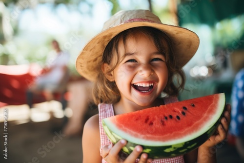 A joyful little girl eats watermelon in nature and smiles. Summer.