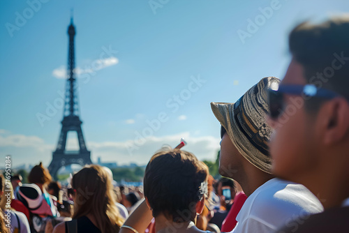 Spectators with flags under the Eiffel Tower, blue sky above.