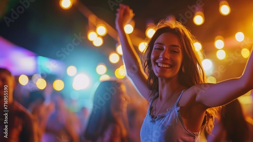 Happy young woman dancing among a group of young people in night club, shiny blurred background, copy space.