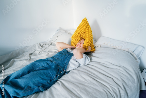 frustrated woman holding pillow over head, screaming feels furious exhausted exasperated laying on bed. mad irritated millennial suffers from head ache lack of self-control. Noise and stress concept