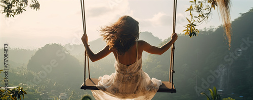Woman swinging in sunset light. Rear view of girl swing against forest background.