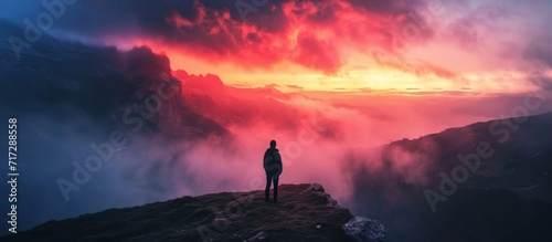 Man witnessing a colorful autumn sunset at Dolomites Landscape, surrounded by foggy hills and a beautiful dusk sky in the Alps.