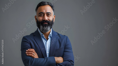 Standing alone on gray with his arms crossed is a proud, self-assured, bearded Indian businessman, investor, wealthy ethnic CEO, corporate executive, professional lawyer, and banker. picture