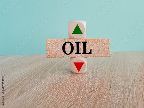 Oil symbol. A wooden cubes with up arrow. Brick block with the concept word OIL . Beautiful blue background, wooden table. Business and brent concept. Copy space.