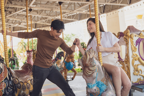 couple asian man and woman dating and riding on horse at Carousel amusement park. Concept happy and lovely life of teenager.
