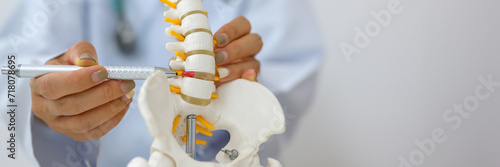 An orthopedic surgeon holds a spinal model as he demonstrates treatment methods for human spinal injuries caused by back pain during a medical consultation.