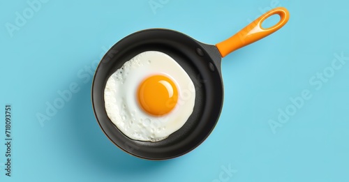 Eggs being fried on a frying pan in the photo on a blue background
