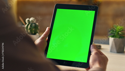 Unknown freelancer looking green screen tablet at desk close up. Man holding tab