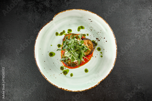 Roasted eggplant slices with tomato and cheese, topped with arugula, from above