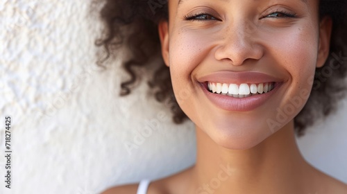 Close up portrait of a smiling young woman with white teeth against white wall