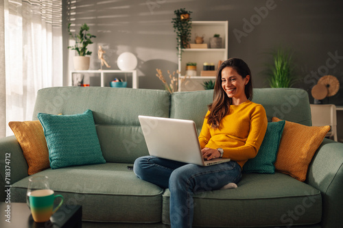 Portrait of a woman using laptop while sitting on a mint couch at home