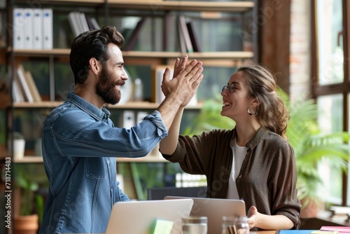 Two happy friendly diverse professionals, teacher and student giving high five standing in office celebrating success, partnership teamwork and team motivation in office, Generative AI