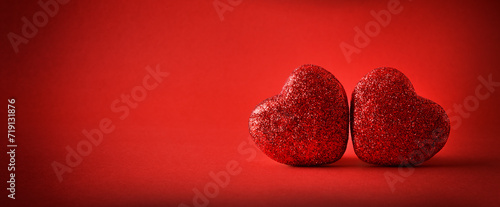 Love background with two red glitter hearts on red background