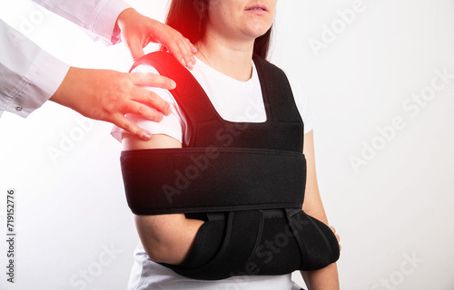 An orthopedic doctor examines a girl patient after a shoulder injury. Bandage on the shoulder joint after shoulder dislocation and bone fracture. Post-traumatic immobilization