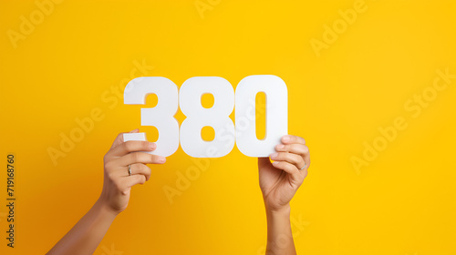 3D 380 number with a female hands font alphabet. White 3D Number 380 with yellow background,AI generated