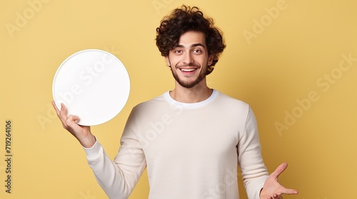 A young artist is posing with a palette in front of a white background while extending his hands to the side and inviting others to come near.