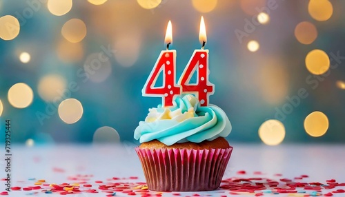 Birthday cupcake with burning lit candle with number 44. Number fortyfour for fortyfour years or fortyfourth anniversary.